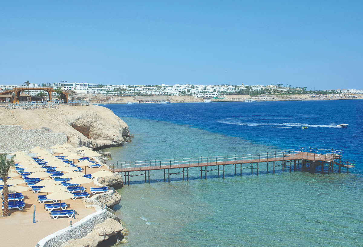 A coastal view from Xperience Sea Breeze Hotel with a small pier and sun loungers.