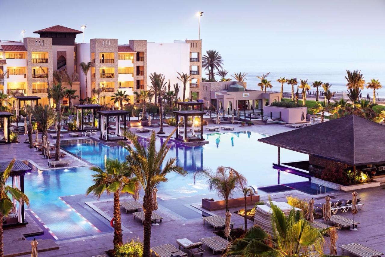Outdoor pool scene with cabanas, palm trees and a pool bar at the Riu Palace Agadir hotel in Morocco