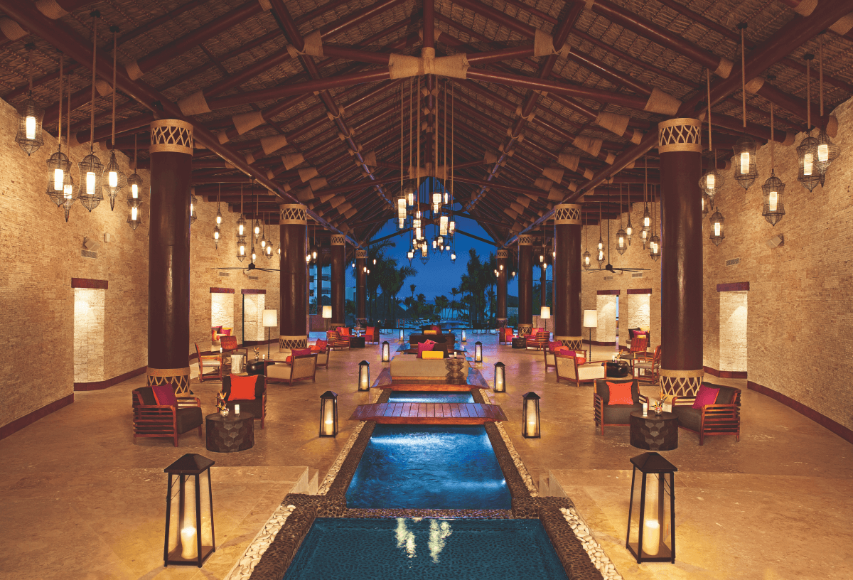 Indoor seating area with low lighting, comfy chairs and water features at the Secrets Cap Cana Resort