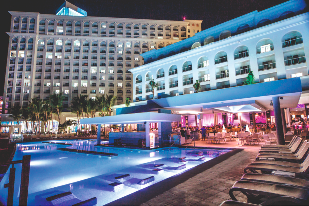 Outdoor pool and swim up bar at the Riu Cancun in the evening with colourful lights