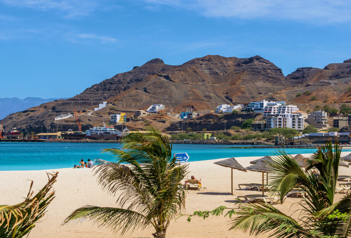 Sandy beach in Sao Vincente with palm treees and mountains in the distance
