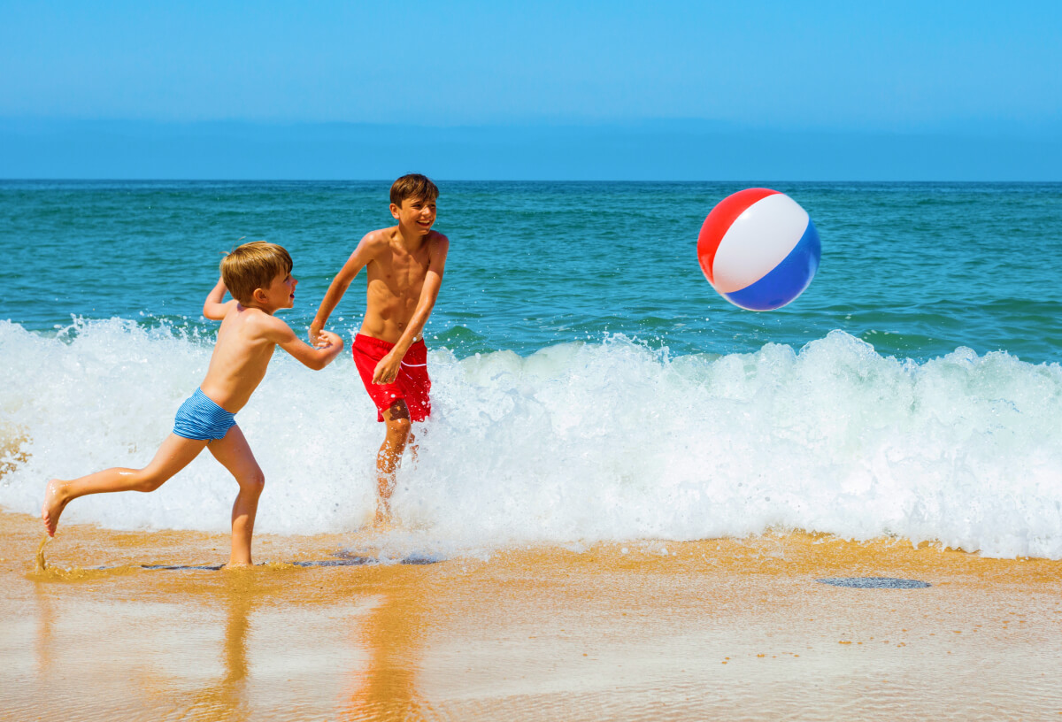 Kids playing on the beach with a beach ball in Sardinia